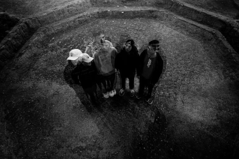 Banda chilena Supertriste posando en una plaza con un filtro en blanco y negro.